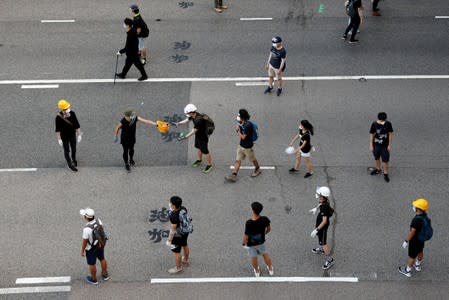 FILE PHOTO: Anti-extradition bill protesters line up to pass down helmet to the frontline during a demonstration near the Legislative Council building on the anniversary of Hong Kong's handover to China in Hong Kong