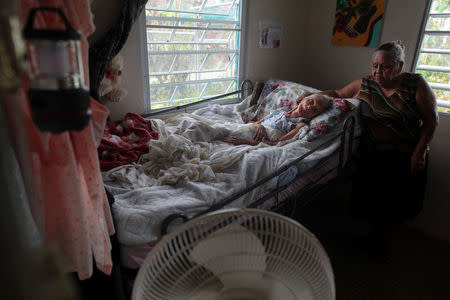 Carmen Rodrigues stands by her bedridden mother, Rosa Maria Torres, 95, after Hurricane Maria destroyed the town's bridge in San Lorenzo, Morovis, Puerto Rico, October 5, 2017. The family are trying to get Torres airlifted out of the town. "If they don't move her out of here, she's going to die," said Carmen Santos, Torres' granddaughter. REUTERS/Alvin Baez