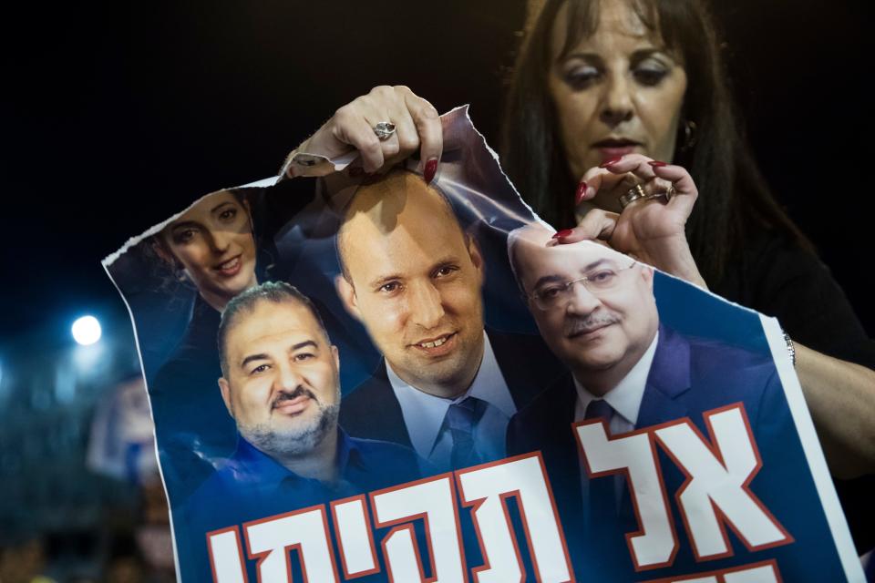 An Israeli woman rips a poster showing photos of expected incoming Prime Minister Naftali Bennett and Mansur Abbas, the head of the United Arab List party and lawmaker Ahmed Tibi during a demonstration against the emerging Israeli government on June 10, 2021 in Jerusalem.