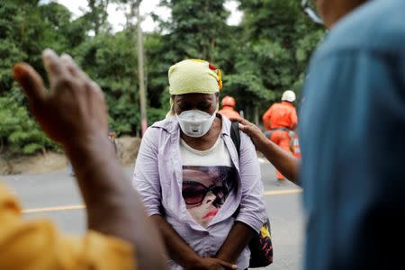 Eufemia Garcia, 48, who lost 50 members of her family during the eruption of the Fuego volcano, prays with members of the evangelical church while searching for her family in San Miguel Los Lotes in Escuintla, Guatemala, June 11, 2018. REUTERS/Carlos Jasso