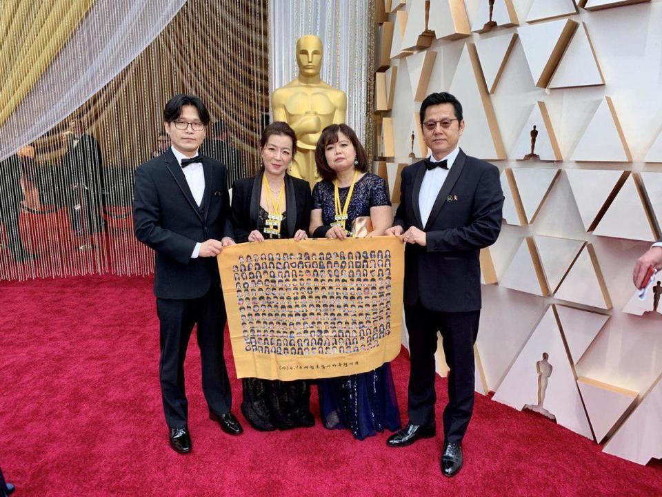李承俊（左）去年帶著世越號罹難者家屬一起走奧斯卡紅毯，黃色布條上印著當年搭上世越號乘客們的大頭照。（李承俊提供）