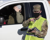 Nickolas Orr of the Idaho National Guard checks in a patient for an outdoor COVID-19 test at Primary Heath Medical Group's clinic in Boise, Idaho, Tuesday, Nov. 24, 2020. Troops direct people outside the urgent-care clinic revamped into a facility for coronavirus patients as infections and deaths surge in Idaho and nationwide. Some 1,000 people have died due to COVID-19, and infections this week surpassed 100,000. (AP Photo/Otto Kitsinger)