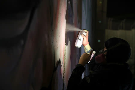 An Australian graffiti artist works on his mural depicting U.S. President Donald Trump and Israeli Prime Minister Benjamin Netanyahu on the controversial Israeli barrier in the West Bank city of Bethlehem October 28, 2017. Picture taken October 28, 2017. REUTERS/Ammar Awad