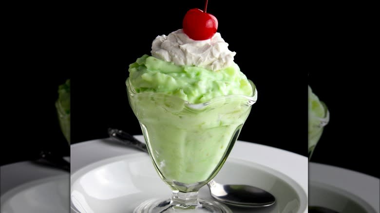 A Watergate salad served in a glass with a cherry on top