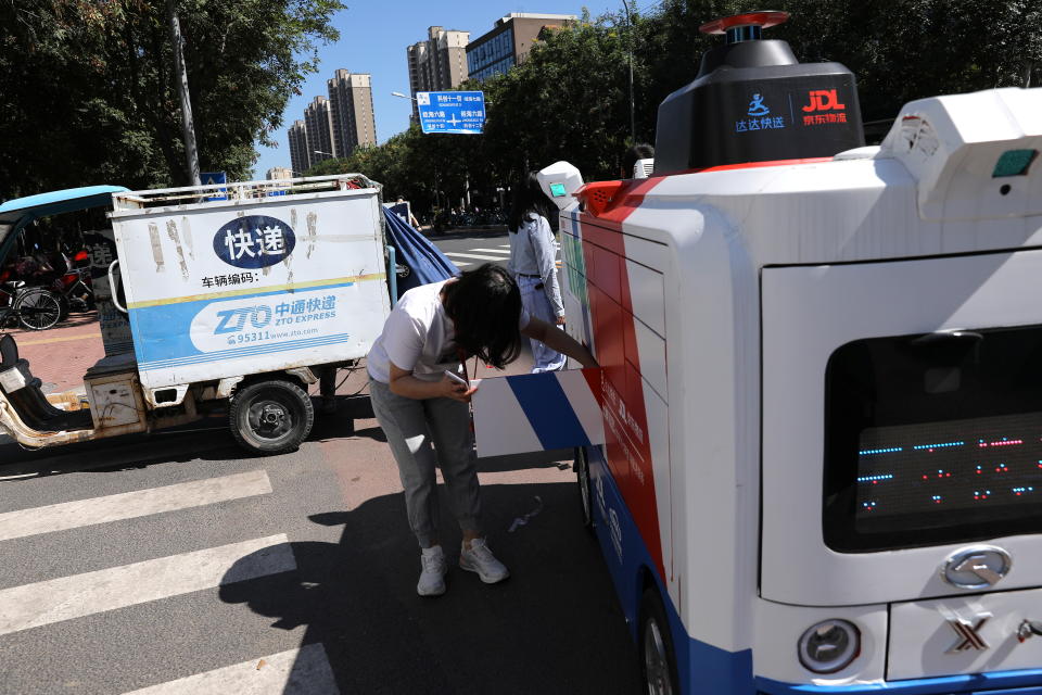 A person fetches a bag of goods from an autonomous delivery vehicle by JD Logistics, the delivery arm of JD.com, in Beijing, China September 22, 2021. Picture taken September 22, 2021. REUTERS/Tingshu Wang