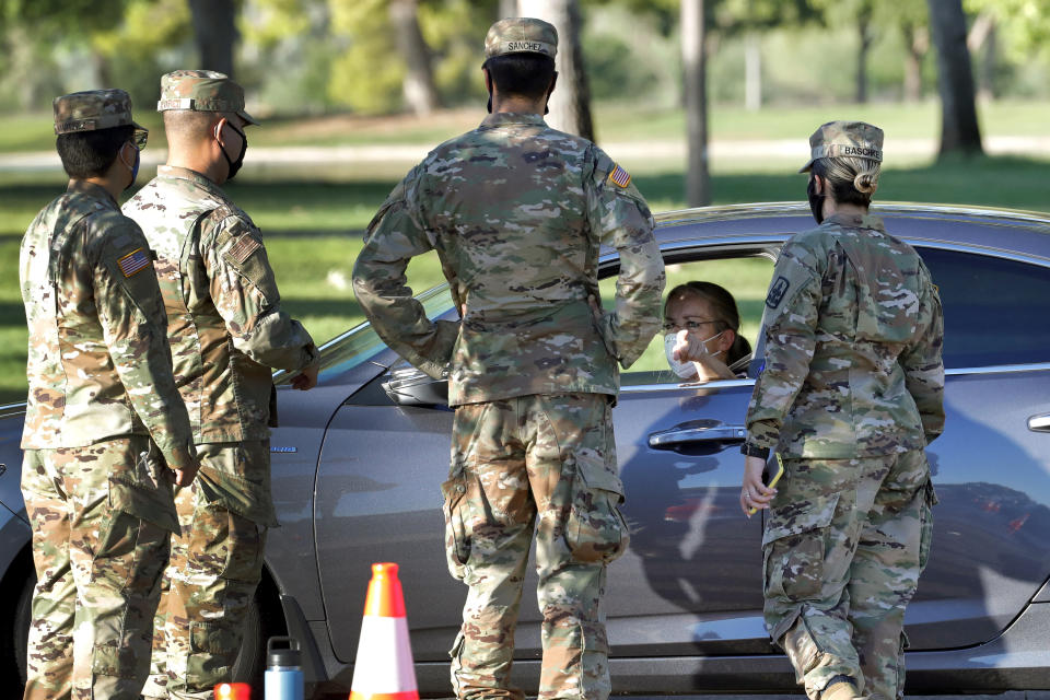 A lady speaks with National Guard solders prior to being tested for the COVID-19 Coronavirus Tuesday, July 28, 2020 at Cesar Chavez City Park in Phoenix. The two-week testing event is aimed at bringing tests to Phoenix's Laveen neighborhood, home to many Latinos and Blacks who have been disproportionately affected by the coronavirus. Latino leaders say governments need to do more to communicate effectively with Hispanic communities to ensure people know where to get tested and encourage them to participate. (AP Photo/Matt York)