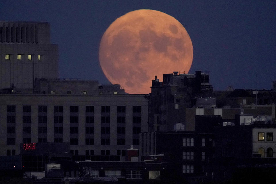 The full harvest moon rises behind downtown buildings, Friday, Sept. 9, 2022, in Kansas City, Mo. (AP Photo/Charlie Riedel)