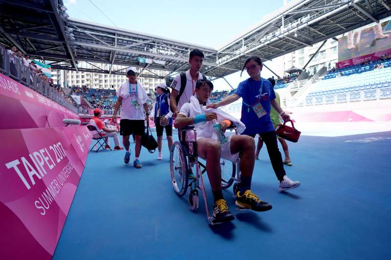 中華隊選手李冠毅因身體不適決定棄賽，離開球場時他坐在輪椅上，向場邊加油的民眾舉手致意。（大專體總提供）