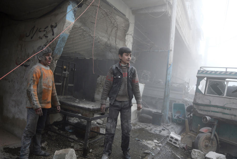 <p>Syrian children covered in dust walk out of a shop following reported Syrian air force strikes in the rebel-held town of Saqba, in the besieged Eastern Ghouta region on the outskirts of the capital Damascus on Feb. 8, 2018. (Photo: Abdulmonam Eassa/AFP/Getty Images) </p>