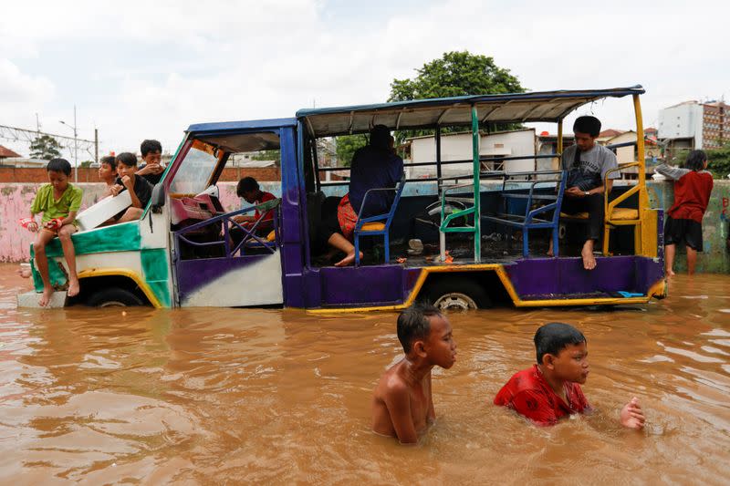 Children play at an area flooded after heavy rains in Jakarta
