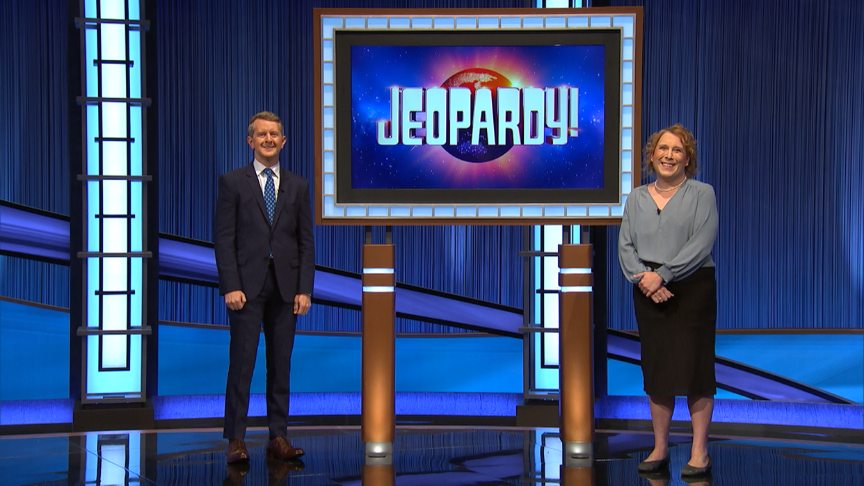 Amy Schneider, a "Jeopardy!" competitor, poses with host Ken Jennings. She has amassed $155,600 in winnings over four days.