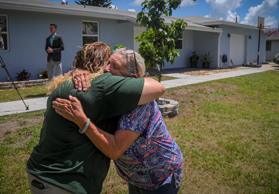 Veronica Herbs, right, hugs Midori Robbins of the Police Athletic League following a reveal of the Herbs family's new home Wednesday at 2531 Sun Up Lane in Lake Worth. Children and staff from PAL along with community businesses worked together for the last couple of months to refinish the Herbs' home that had burned down.