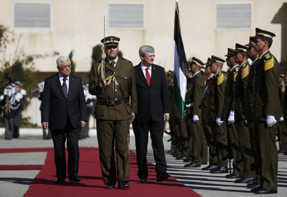 Palestinian President Abbas walks with Canadian Prime Minister Harper as they review an honour guard ceremony in Ramallah