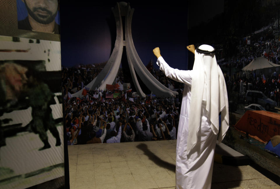 In this picture taken Monday, Oct. 28, 2013, a Bahraini man gestures at a mimic scene reminiscent of the early days of pro-democracy rallies at the since-demolished and blockaded Pearl monument, while visiting an interactive museum-style exhibition opened by an opposition group in Manama, Bahrain. Riot police in Bahrain stormed the exhibition on Wednesday, Oct. 30, that is dedicated to the Arab Spring-inspired uprising in the violence-wracked Gulf nation where crackdowns have strained ties between the ruling dynasty and their allies in Washington and elsewhere in the West. (AP Photo/Hasan Jamali)
