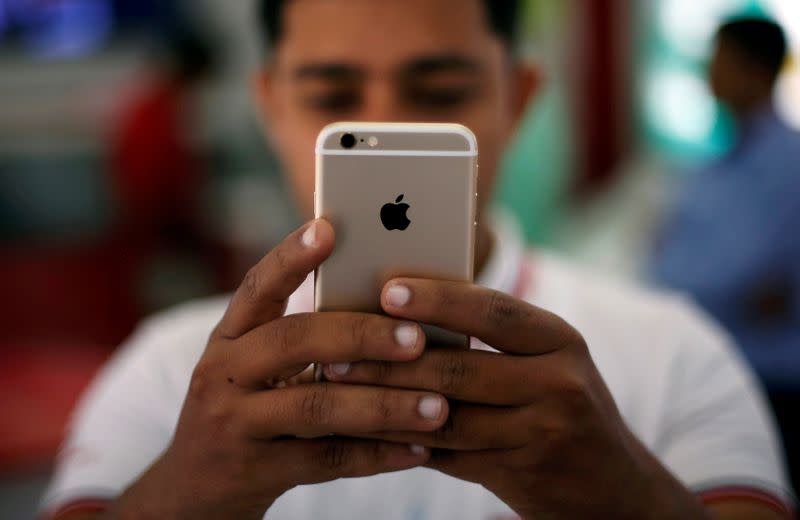 FILE PHOTO: A salesman checks a customer's iPhone at a mobile phone store in New Delhi