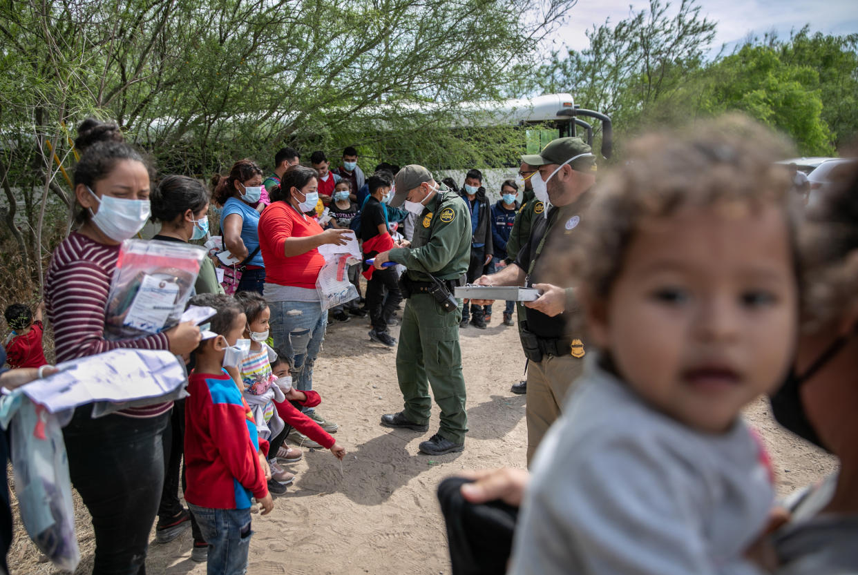 U.S. Border Patrol agents question a group of migrant families and unaccompanied children after they crossed the Rio Grande into Texas on March 25, 2021 in Hildago, Texas. (John Moore/Getty Images)