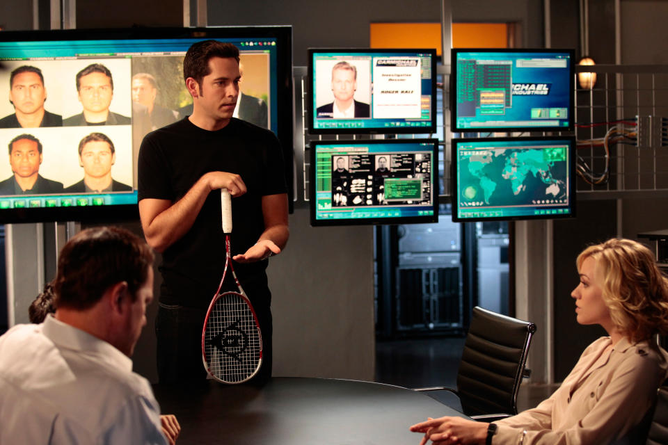 people in a conference room looking at screens with people's mug shots