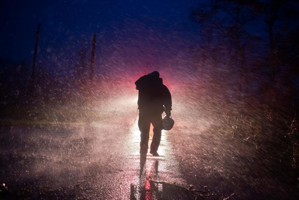 Fire chief walks back to his fire truck in the rain as firefighters cut through trees on the road in Bourg, Louisiana, as Hurricane Ida passes