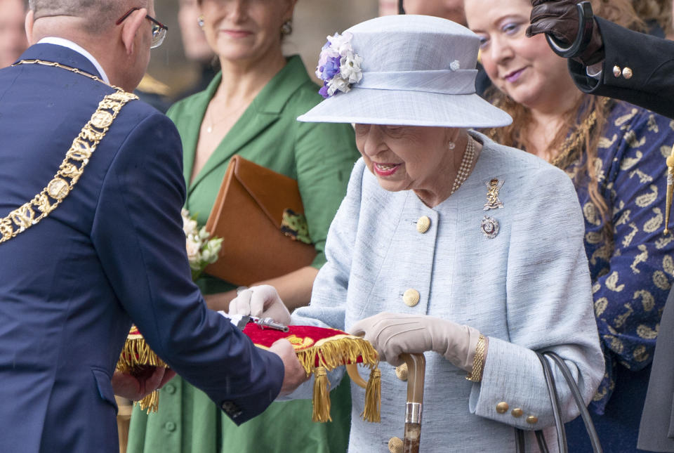 La reina Isabel II de Gran Bretaña inspecciona las llaves presentadas por Lord Provost Robert Aldridge, a la izquierda, durante la "ceremonia de las llaves" en la explanada del Palacio de Holyroodhouse en Edimburgo, el lunes 27 de junio de 2022, como parte de su tradicional viaje a Escocia para la semana de Holyrood. (Jane Barlow/PA vía AP)