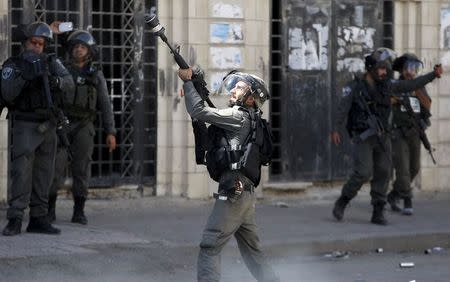 An Israeli border police fires at Palestinian protesters during clashes following a protest against the Israeli police raid on Jerusalem's al-Aqsa mosque on Tuesday, in the occupied West Bank city of Hebron September 18, 2015. REUTERS/Mussa Qawasma