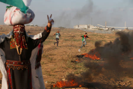 Palestinians hurl stones at Israeli troops during a protest calling for lifting the Israeli blockade on Gaza and demanding the right to return to their homeland, at the Israel-Gaza border fence, east of Gaza City September 14, 2018. REUTERS/Mohammed Salem