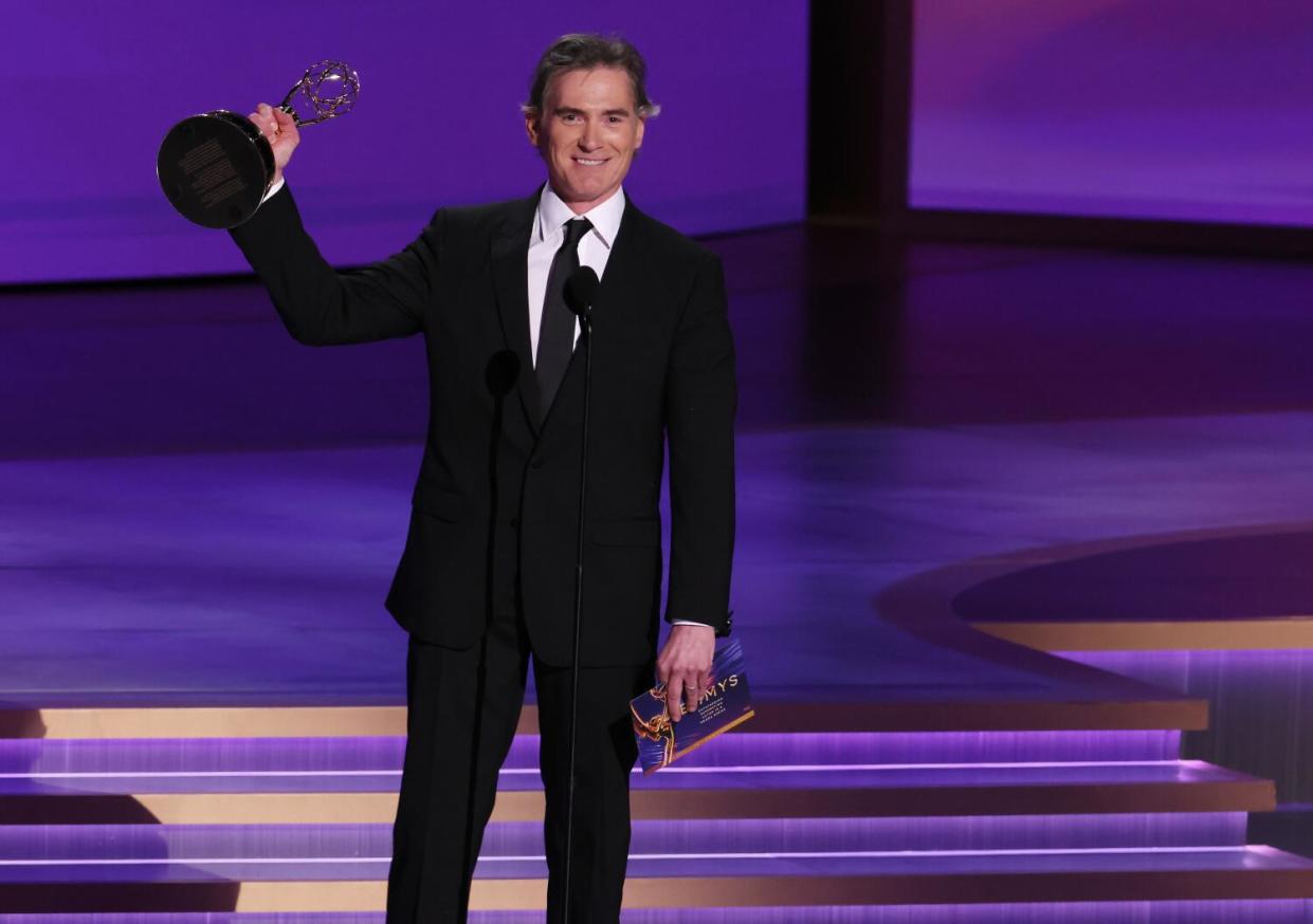 Billy Crudup holds up an Emmy onstage