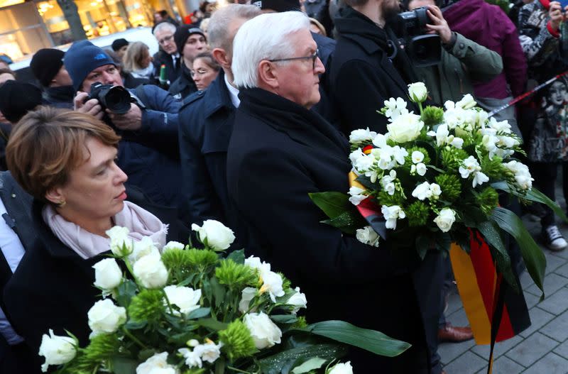 Man lays down flowers at one of the crime scenes following a shooting in Hanau