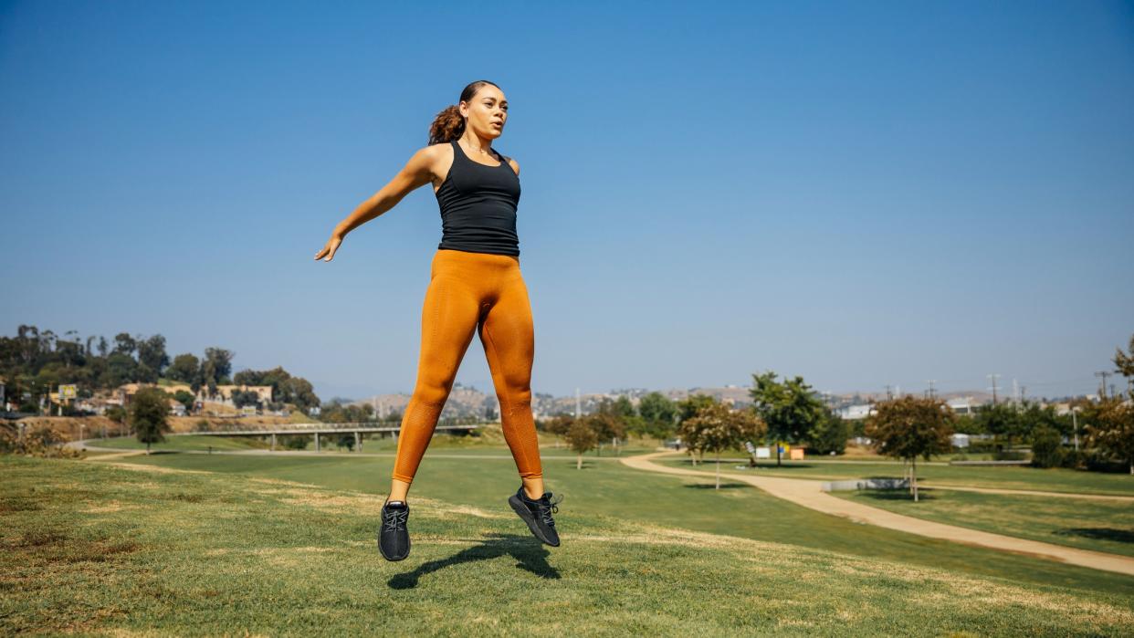  Woman doing a squat jump outdoors 