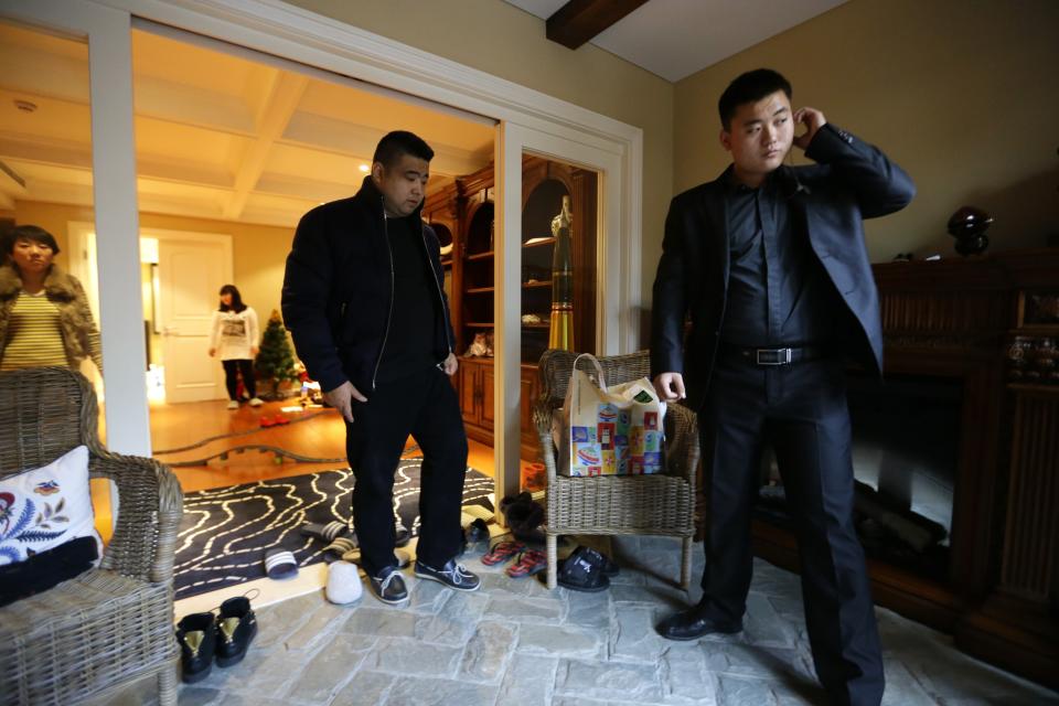 Bodyguard Han, who was hired from Tianjiao Special Guard/Security Consultant, checks his earphone as his employer Zhang prepares to leave home on the outskirts of Beijing