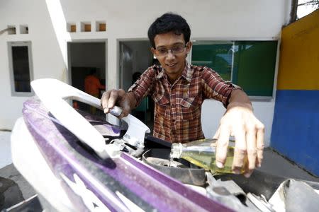 Hamidi pours fuel, derived from burning plastic waste, into his motorcycle at the workshop of the TPA Rawa Kucing in Tangerang, Banten province, Indonesia, March 17, 2016. REUTERS/Beawiharta