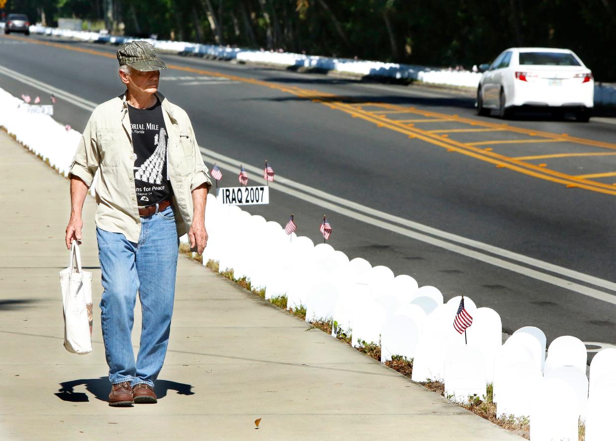 Randy Kaufman, an Army veteran of the Vietnam War, walks past the personalized tombstones in the annual Memorial Mile set up by Veterans For Peace along Northwest Eighth Avenue in Gainesville in 2019.