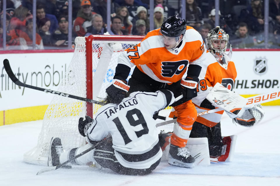 Los Angeles Kings' Alex Iafallo (19) collides with Philadelphia Flyers' Tony DeAngelo (77) and Carter Hart (79) during the third period of an NHL hockey game, Tuesday, Jan. 24, 2023, in Philadelphia. (AP Photo/Matt Slocum)