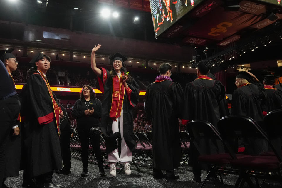 A graduate waves to onlookers during commencement for the University of Southern California's Viterbi School of Engineering Friday, May 10, 2024, in Los Angeles. (AP Photo/Ryan Sun)