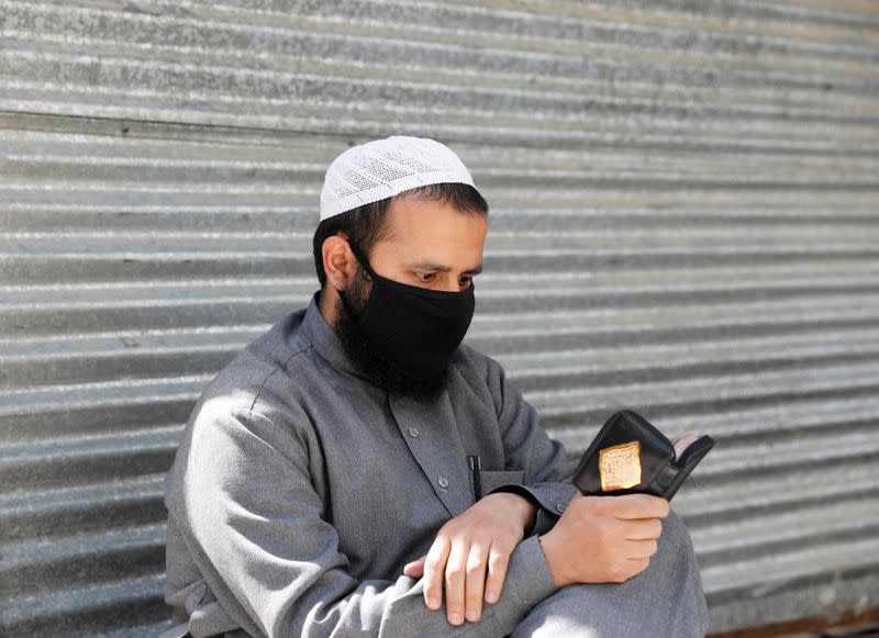 An Afghan man reads the Koran on the first day of the holy fasting month of Ramadan, amid the spread of the coronavirus disease (COVID-19), in Kabul, Afghanistan