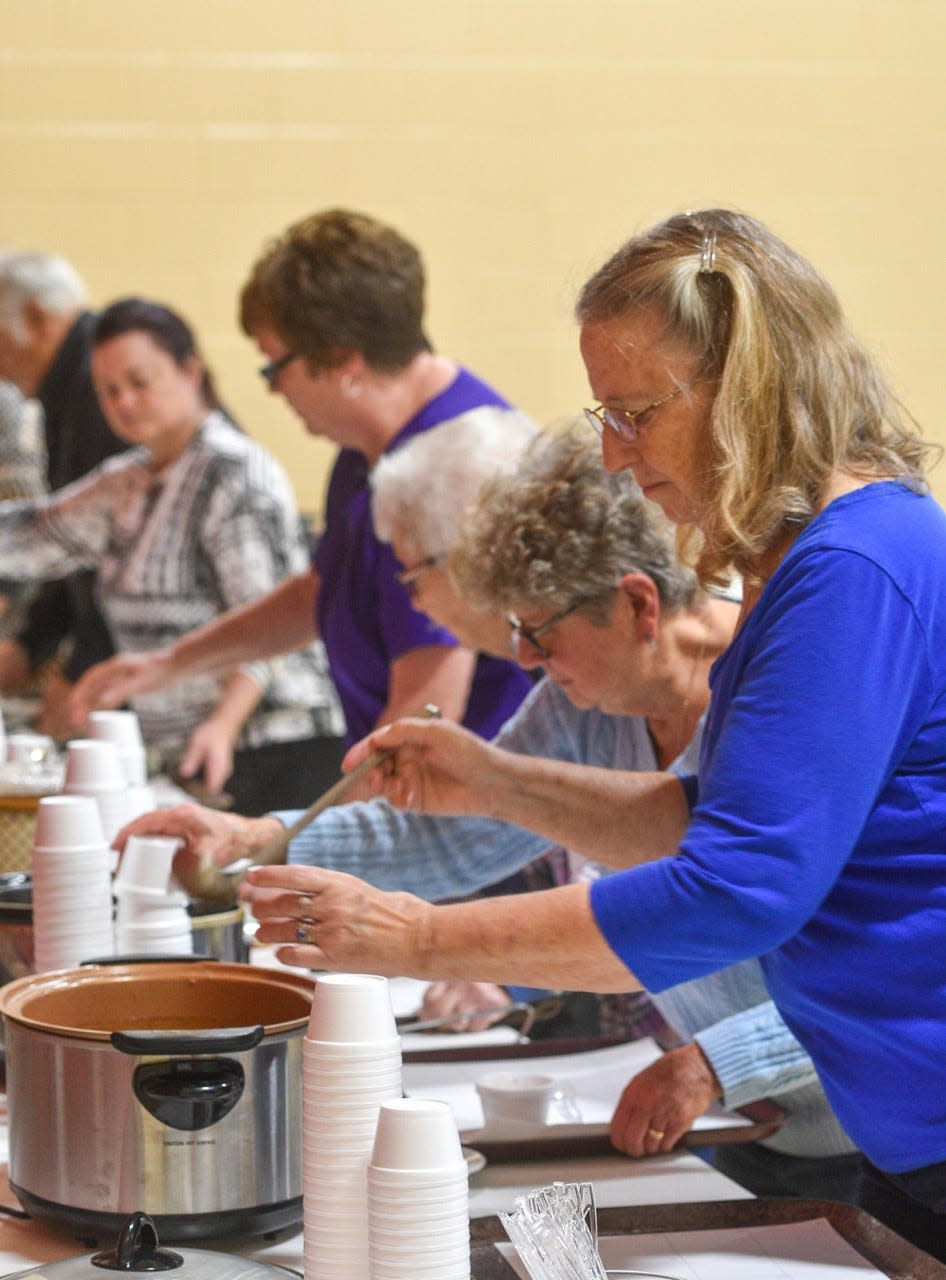 St. Ann parishioners and local residents pour ladles of chicken noodle soup, shrimp bisque and potato cheddar soup into sample-size cups.
