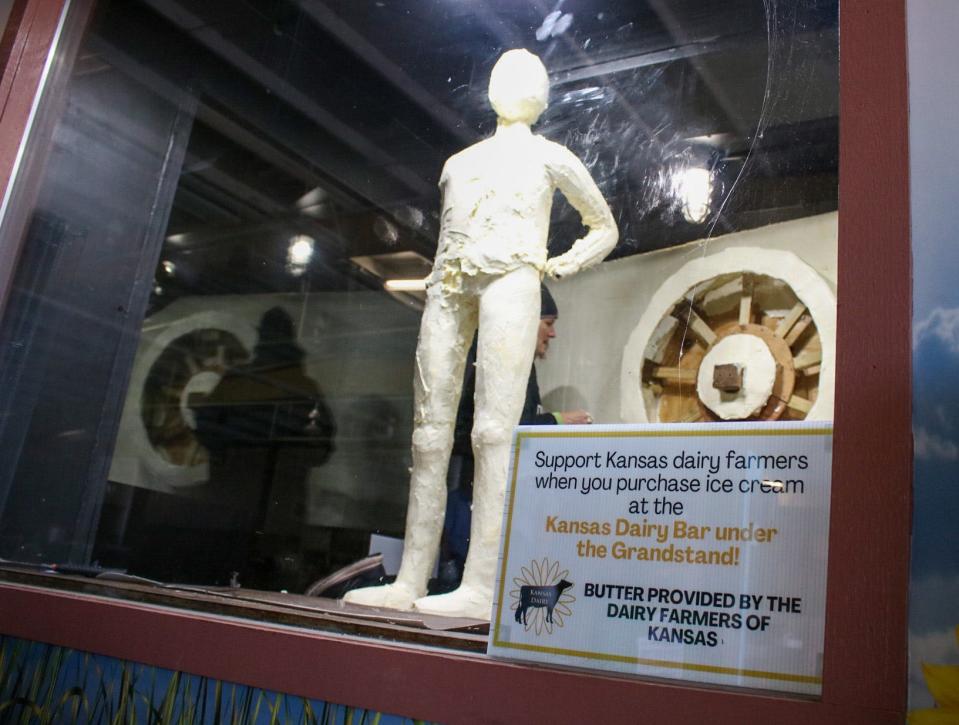 An early rendition of the 2023 Kansas State Fair butter sculpture is seen through large panels of glass. The thick glass panels keep the room cool enough for the butter to keep its shape.