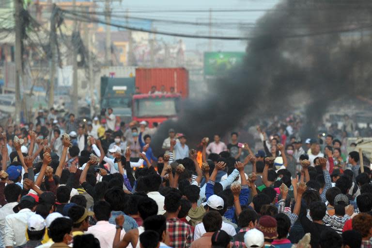 Cambodian garment workers carry rocks as they shout slogans after a brief clash with police during a protest to demand higher wages in front of a factory in Phnom Penh on January 2, 2014