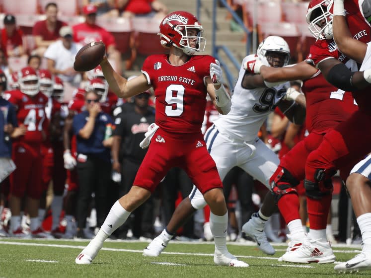 Fresno State quaterback Jake Haener throws a pass past Connecticut defenders.