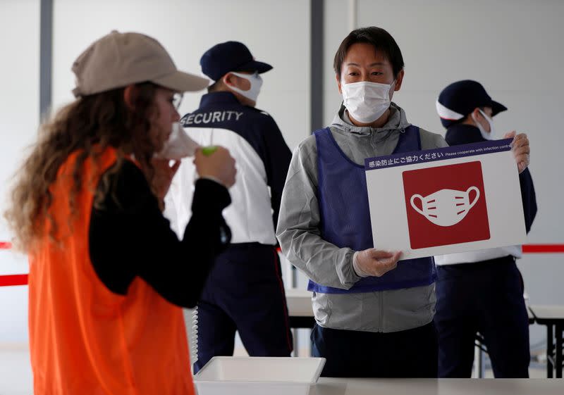 FILE PHOTO: Officials wearing protective masks conduct a test session of screening measures for Tokyo Olympic games spectators,i ncluding coronavirus disease (COVID-19) countermeasures at Tokyo Big Sight, Japan October 21, 2020