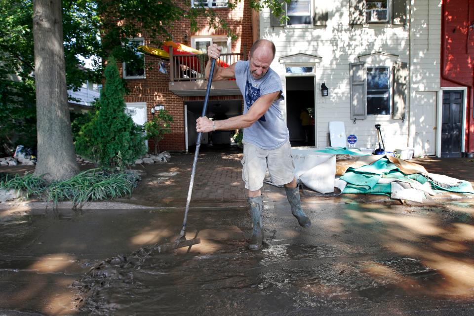 Michael Snyder scrapes away the mud after flooding from the Susquehanna River caused by the remnants of Tropical Storm Lee on Sept. 10, 2011, in Harrisburg, Pa.