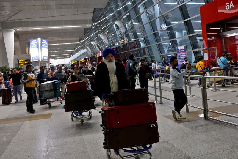 Travellers push trolleys with their luggage at the departure area of the Indira Gandhi International Airport in New Delhi