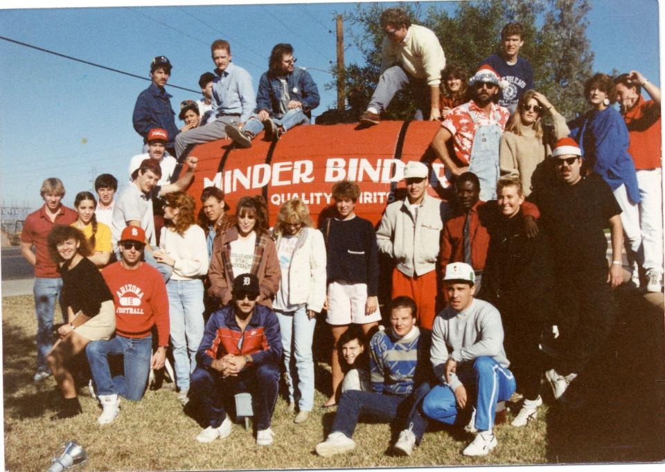 Robin Wilson of Gin Blossoms is seated on top of the iconic water wagon outside Minder Binders Bar and Grill in Tempe with a group of employees.