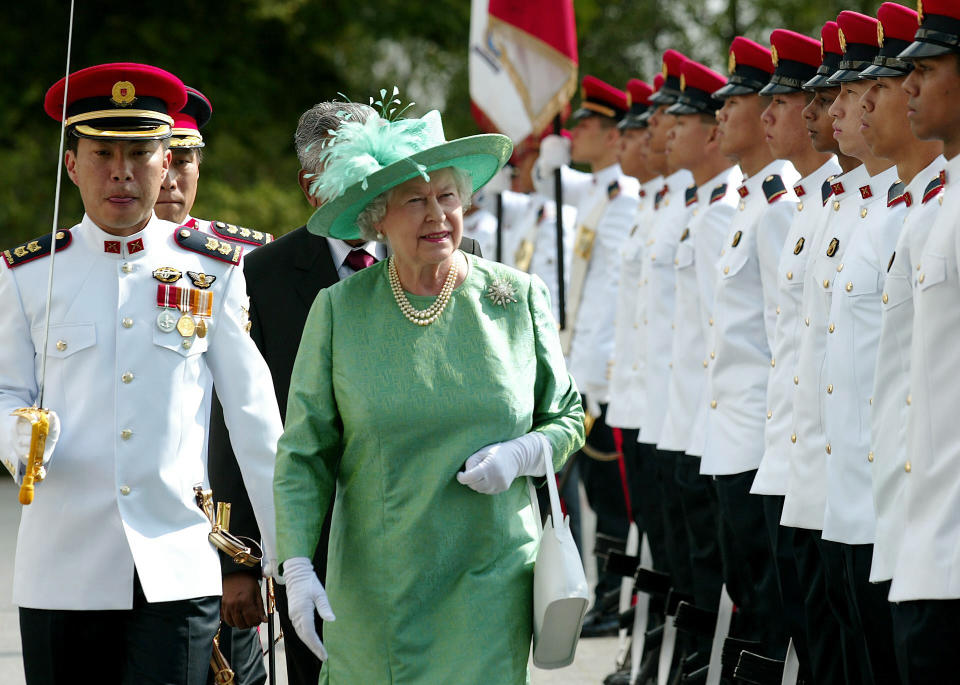 Queen Elizabeth II inspects a guard of the Singapore Armed Forces Provost Unit during a visit to the Presidential Palace Friday March 17, 2006 as part of two day state visit to the former Crown Colony in south-east Asia. See PA story ROYAL Singapore. PRESS ASSOCIATION Photo. Photo credit should read: Gareth Fuller / PA.   (Photo by Gareth Fuller - PA Images/PA Images via Getty Images)