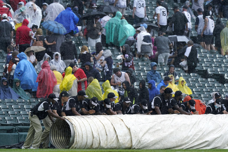 The Chicago White Sox grounds crew puts a tarp on the field during a rain delay in the third inning of a baseball game against the Seattle Mariners in Chicago, Saturday, June 26, 2021. (AP Photo/Nam Y. Huh)