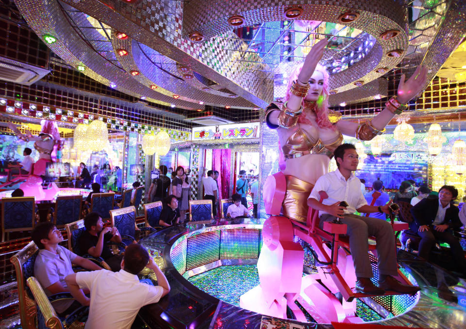 A customer (R) is seated on a 3.6 metre-high custom-made female robot at the newly opened "Robot Restaurant" in Kabukicho, one of Tokyo's best known red light districts, August 16, 2012. It's show time at the "Robot Restaurant" a new and high-tech take on the city's decades-old cabaret scene that puts a friendly, if unusual, face on the robot technology in which Japan is a world leader. Picture taken August 16, 2012. REUTERS/Yuriko Nakao (JAPAN - Tags: SOCIETY ENTERTAINMENT FOOD TPX IMAGES OF THE DAY)