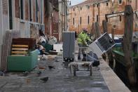 People remove damaged items from an alley in Venice, northern Italy, Monday, Nov. 18, 2019. Venetians have been coping with almost a week of exceptional tides that flooded most of the city and caused damage that has been estimated at hundreds of millions of euros (dollars). (Andrea Merola/ANSA via AP)