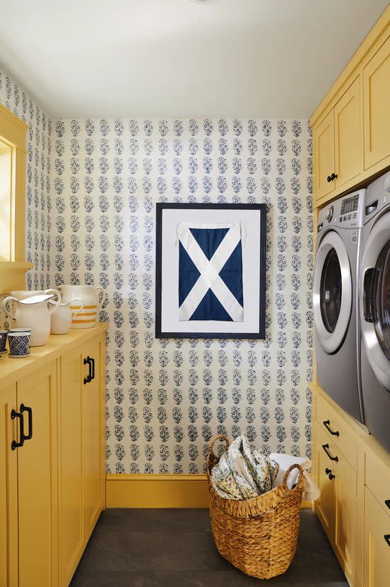 yellow laundry room with mughal flower wallpaper and framed vintage blue and white sailing flag