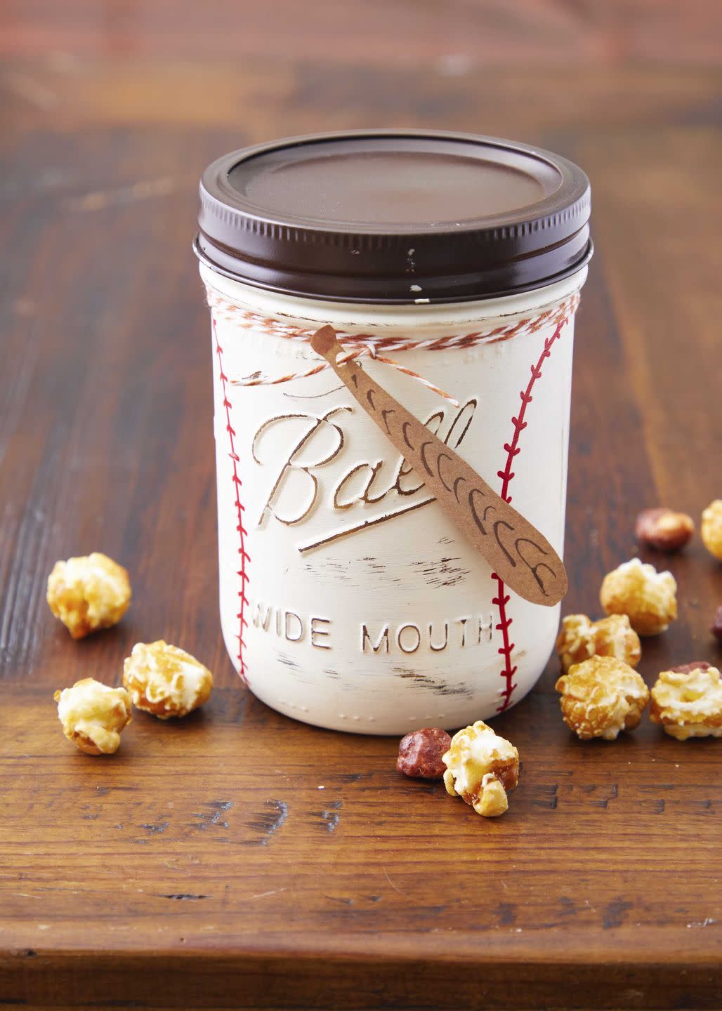 a mason jar decorated like a baseball with a paper bat tag filled with candied popcorn