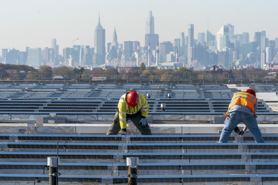 Electricians with IBEW Local 3 install solar panels on top of the Terminal B garage at LaGuardia Airport, Nov. 9, 2021, in New York. (AP Photo/Mary Altaffer, File)