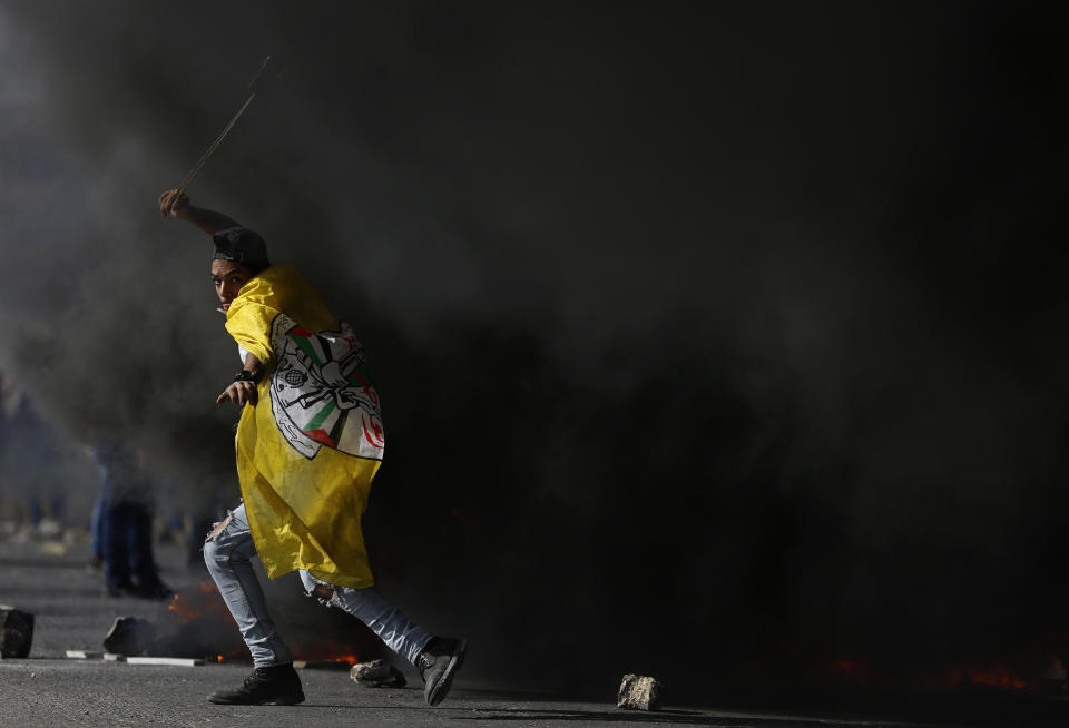 Palestinian demonstrator uses sling shot as clashes broke out with Israeli troops during the protest against the U.S. announcement that it no longer believes Israeli settlements violate international law., at checkpoint Beit El near the West Bank city of Ramallah, Tuesday, Nov. 26, 2019, (AP Photo/Majdi Mohammed)